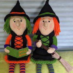 Pode incluir: Duas bonecas de bruxa de tricô com chapéus pretos, uma segurando um livro que diz "Spell Book" e a outra segurando uma vassoura.