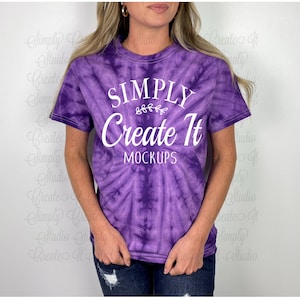 May include: A purple tie-dye t-shirt with the text "SIMPLY Create It MOCKUPS" in white. The shirt has a crew neck and short sleeves. The tie-dye pattern is a spiral design.