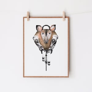 May include: Watercolor print of an okapi riding a bicycle. The okapi's head and body are brown and white, with large ears and a striped pattern on its legs. The bicycle is black and white, and the artwork is framed in a brown wooden frame.