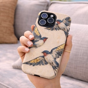 Könnte beinhalten: Beige Handyhülle mit einem Aquarelldesign von Schwalben mit blauen, roten und goldenen Akzenten. Die Schwalben sind im Flug mit ausgebreiteten Flügeln dargestellt. Die Hülle hat ein mattes Finish und ein schützendes Design.