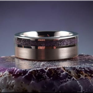 May include: A white ceramic mug with a black handle and the text "But First, Coffee" in a bold, black font. The mug is set against a blurred background, suggesting a cozy setting.