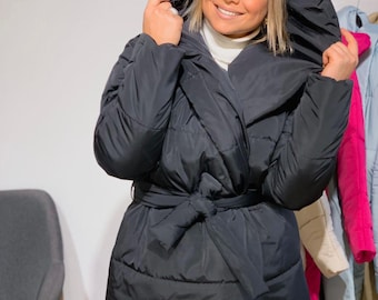 May include: A black hooded puffer jacket with a belted waist. The jacket has a quilted design and a large hood.
