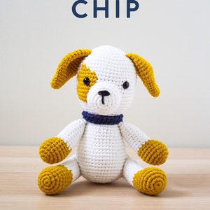 Peut inclure: Un jouet pour chien en crochet fait à la main, blanc, jaune moutarde et bleu marine. Le chien a un corps blanc, des oreilles et des pattes jaune moutarde et un collier bleu marine. Le texte "love & stitch" et "PUPPY CHIP" sont au-dessus du jouet.