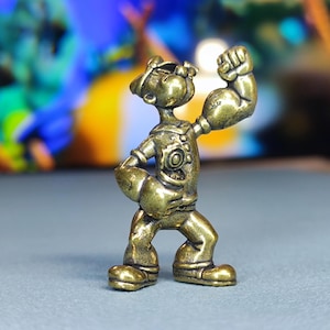 Figura de latón vintage de un marinero en pose dinámica, elaborada con finos detalles. Un objeto de colección atemporal para los entusiastas marítimos.
