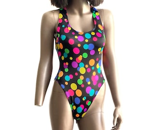 May include: A black one-piece swimsuit with a colorful polka dot pattern. The dots are in various shades of pink, blue, green, yellow, and orange.