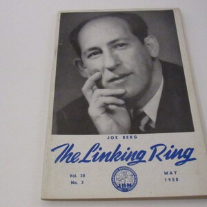 May include: A black and white photo of a man with a serious expression, looking at the camera. The photo is on the cover of a magazine called "The Linking Ring" with the text "Joe Berg" and "Vol. 38 No. 3" and "May 1958".