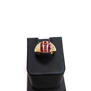 May include: A gold ring with a band of small diamonds and a row of red ruby stones set in a curved design.