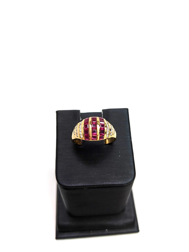 May include: A gold ring with a band of small diamonds and a row of red ruby stones set in a curved design.