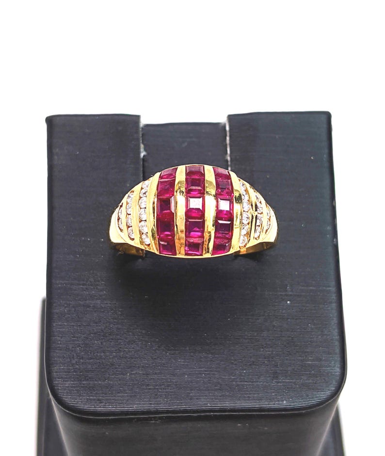 May include: A gold ring with a row of red ruby stones and a row of clear diamonds on each side.