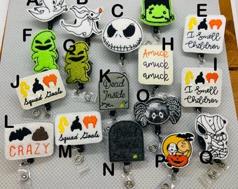 May include: A set of 16 Halloween-themed retractable badge holders. The holders feature various characters and designs, including ghosts, pumpkins, skeletons, and a spider. Some of the holders have text, such as "Squad Goals", "Dead Inside", and "I Smell Children".