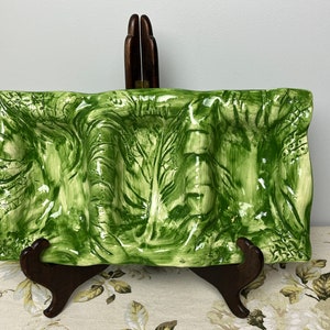 May include: A green ceramic serving dish with a textured, leafy design. The dish has three indented sections and is perfect for serving appetizers or snacks.