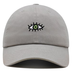 May include: A gray baseball cap with an embroidered eye design. The eye is white with a green iris and black eyelashes.