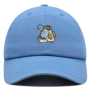 May include: A light blue baseball cap with an embroidered cartoon anglerfish on the front.