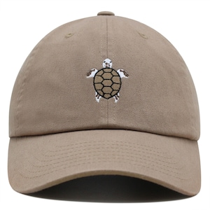May include: A khaki baseball cap with an embroidered brown and white turtle design.