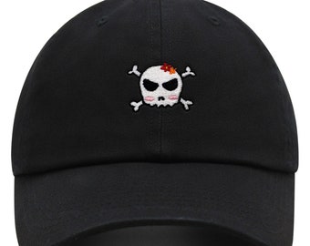May include: Black baseball cap with an embroidered white skull and crossbones design. The skull has a pink blush and a red flower on top.