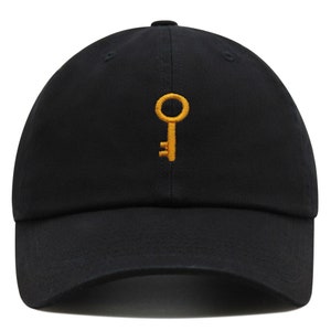 May include: A black baseball cap with a gold key embroidered on the front.
