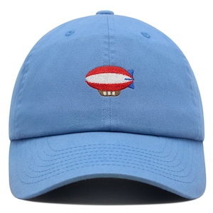 Puede incluir: Una gorra de béisbol azul claro con un diseño de dirigible bordado en rojo, blanco y azul.