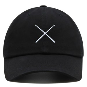 Op de afbeelding: Een zwarte baseballpet met een wit geborduurd ontwerp van twee drumsticks die in een 'X' vorm gekruist zijn.
