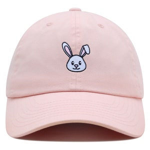 May include: A pink baseball cap with an embroidered white bunny face on the front.