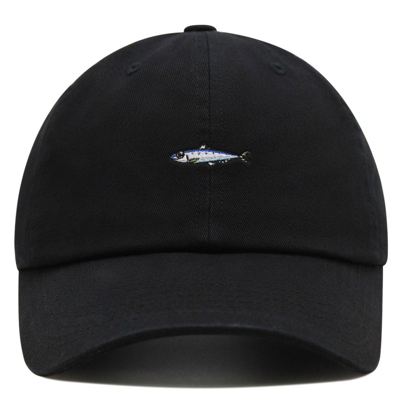 May include: Black baseball cap with a small embroidered fish design in shades of blue, white, and yellow. The cap has a curved brim and a classic six-panel construction. A casual accessory for everyday wear.