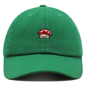 May include: A green baseball cap with a small embroidered mushroom design. The mushroom is red with white spots and has a smiling face.
