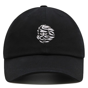 May include: A black baseball cap with a white embroidered design of a face with a beard and hair blowing in the wind.