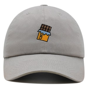 Könnte beinhalten: Eine graue Baseballkappe mit einem gestickten Schokoladenriegel-Design. Der Schokoladenriegel ist braun mit einer gelben Verpackung und das Wort "CHO" ist auf der Verpackung sichtbar.