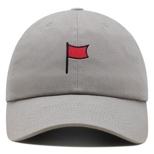 Könnte beinhalten: Eine graue Baseballkappe mit einer aufgestickten roten Flagge auf der Vorderseite.