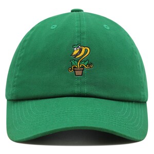 May include: A green baseball cap with an embroidered cartoon of a yellow plant with a toothy grin and a brown pot.
