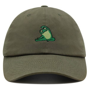 Könnte beinhalten: Eine grüne Baseballkappe mit einem gestickten Bild eines grünen Frosches, der Yoga macht.