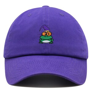 Puede incluir: Gorra de béisbol morada con una rana verde bordada que lleva un sombrero de mago morado.