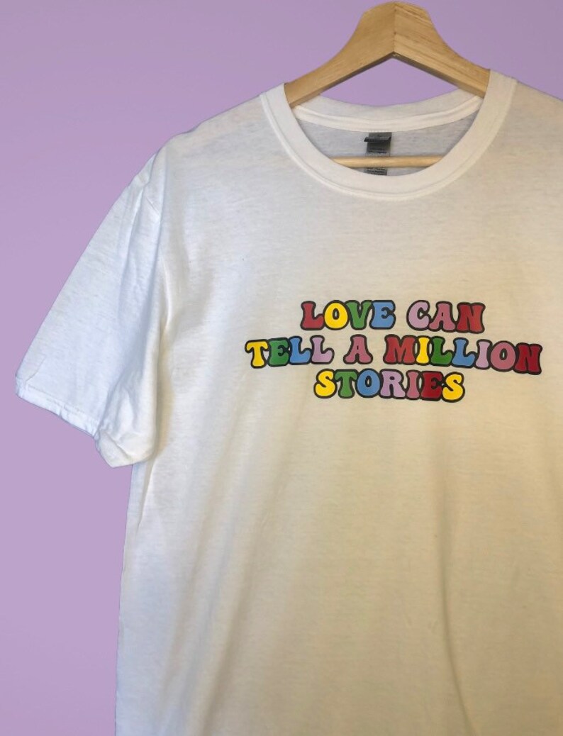 May include: White t-shirt with the text "LOVE CAN TELL A MILLION STORIES" printed in colorful letters.