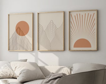 May include: Three minimalist art prints in wooden frames, featuring abstract line drawings of mountains and a sun in shades of brown and orange.