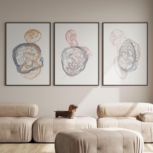 May include: Three framed abstract art prints with a white background and black frames. The prints feature a series of overlapping circles in shades of blue, pink, and gold.