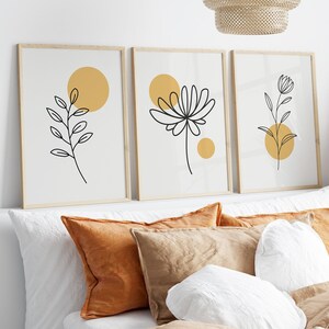 May include: Three framed prints with minimalist line drawings of flowers and leaves on a white background. Each print features a yellow circle.
