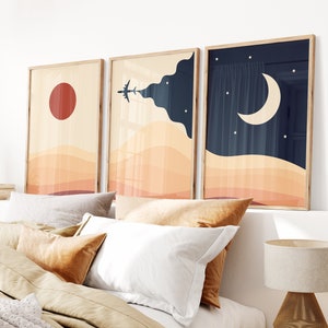 Set of three minimalist desert posters featuring abstract sand dunes, red sun, airplane in the sky, and moon with stars. Modern boho wall art in warm beige and navy tones.