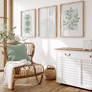 Pu&ograve; includere: Un mobile bianco con due cassetti e due ante, una sedia in vimini con un cuscino verde e una coperta, e tre stampe incorniciate con disegni astratti in verde e bianco.