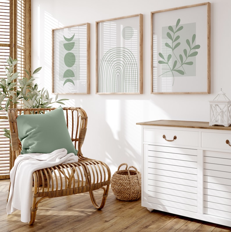 Pu&ograve; includere: Un mobile bianco con due cassetti e due ante, una sedia in vimini con un cuscino verde e una coperta, e tre stampe incorniciate con disegni astratti in verde e bianco.