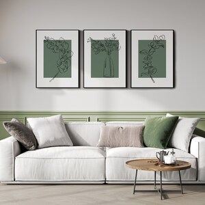 May include: Three black framed prints with white mounts and green backgrounds featuring line drawings of flowers and greenery.