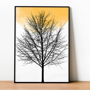 May include: A black and white print of a bare tree with a yellow watercolor circle behind it. The print is framed in a black frame.