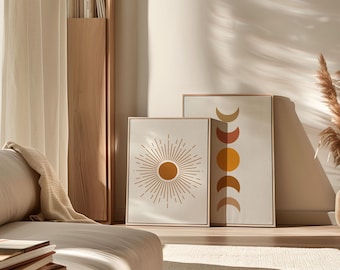 May include: Two framed canvas art prints. One features a sunburst design with a central orange circle and radiating lines. The other displays a series of crescent shapes in shades of orange and yellow. Both are in neutral tones.