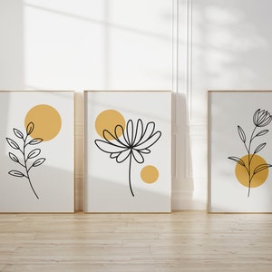 May include: Three framed prints with minimalist line drawings of plants and yellow circles on a white background.