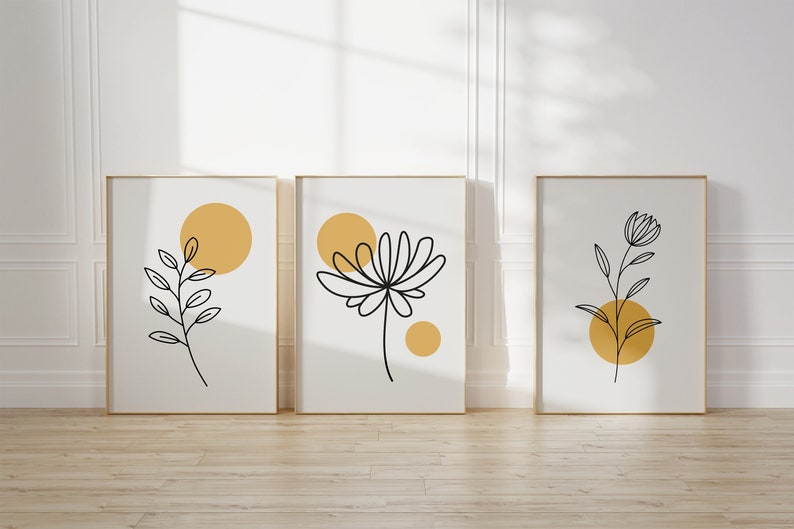 May include: Three framed prints with minimalist line drawings of plants and yellow circles on a white background.
