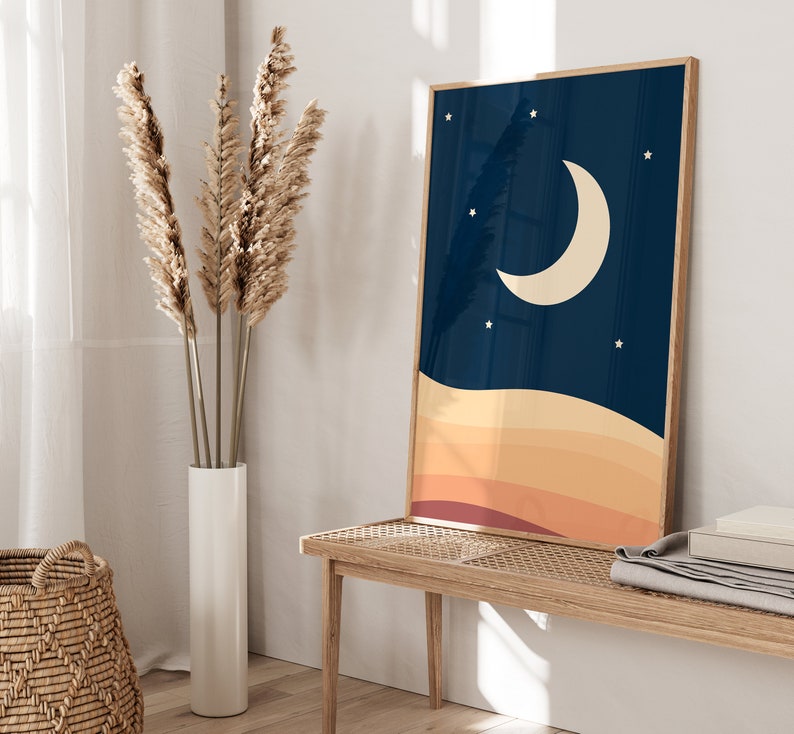 以下が含まれることがあります： 濃い青色の背景に三日月と星が描かれた額装されたプリント。オレンジ、イエロー、レッドのグラデーションで重ねられた夕焼けが描かれている。