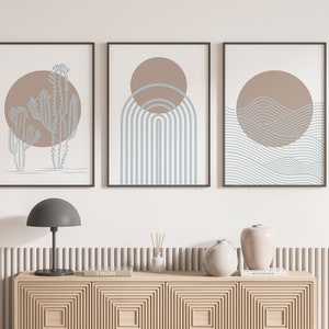 May include: Three minimalist art prints with a brown and blue color scheme. The prints feature a cactus, a rainbow, and waves.