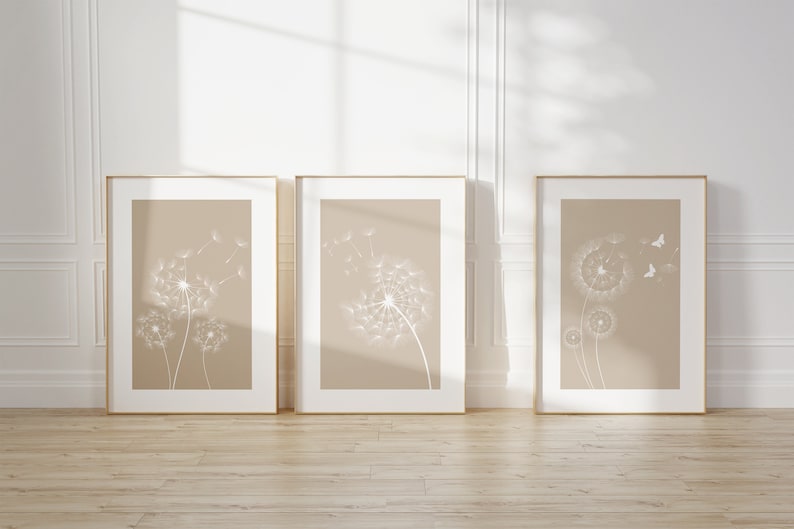 May include: Three framed prints with a beige background and white dandelion illustrations. The dandelions are in various stages of blowing away with seeds.