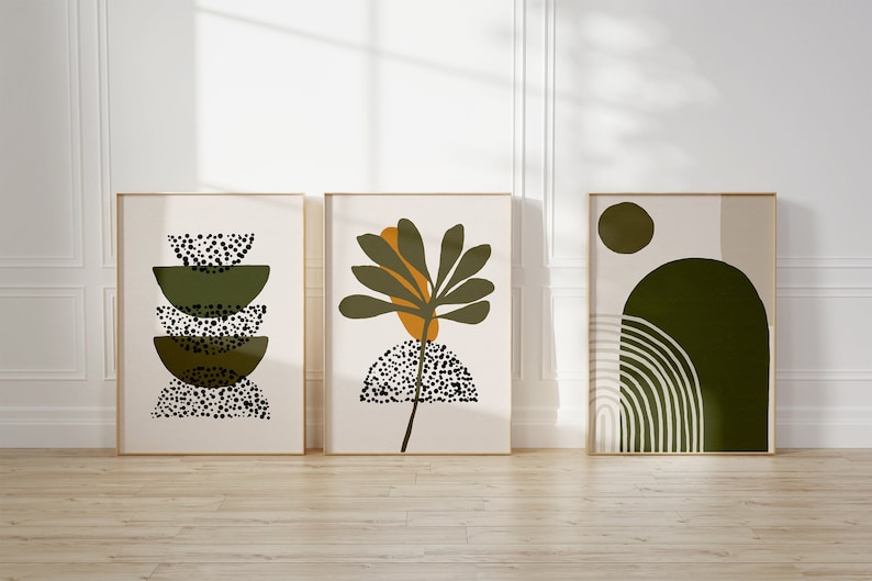 May include: Three framed abstract art prints with a minimalist design featuring green, brown, and white colors. The prints feature geometric shapes, a stylized plant, and a circle.