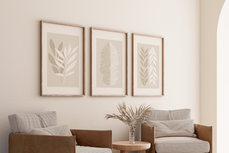 May include: Three framed prints with minimalist illustrations of leaves in shades of beige and white on a light beige background.
