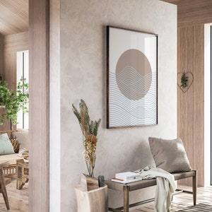 May include: A minimalist wall art print with a brown circle and blue wavy lines on a white background. The print is framed in a dark wood frame and hangs on a light gray wall.