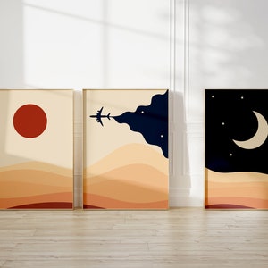 Set of three minimalist desert posters featuring abstract sand dunes, red sun, airplane in the sky, and moon with stars. Modern boho wall art in warm beige and navy tones.